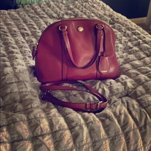 A wine colored coach mid-sized purse with strap.